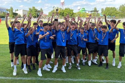 Jucătorii echipei de fotbal juniori U16 ACS Galaxy Timișoara bucurându-se și ridicând trofeul de campioni naționali ai Seriei 7 pe stadionul Electrica.