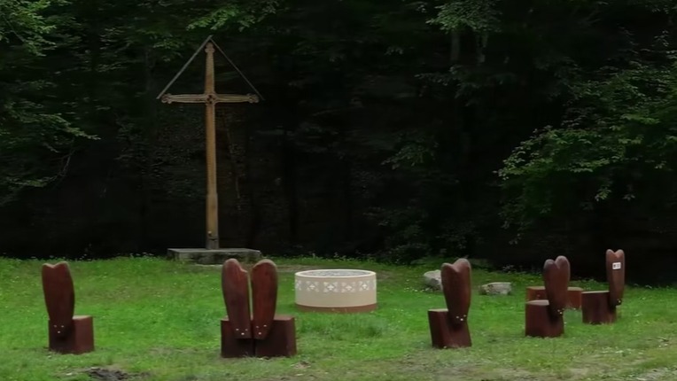 Mobilier din lemn masiv format din masă și bănci rustice, instalat ca punct de odihnă pe marginea traseului turistic Transluncani.