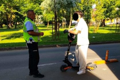 Polițiști locali în Timișoara opgând un trotinetist în trafic pentru verificări și aplicarea de amenzi.