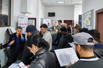 Persoane analizând listele cu locuri de muncă vacante la sediul Agenției pentru Ocuparea Forței de Muncă.
