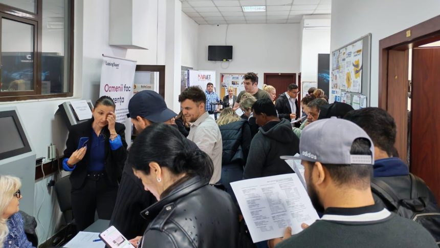 Persoane analizând listele cu locuri de muncă vacante la sediul Agenției pentru Ocuparea Forței de Muncă.