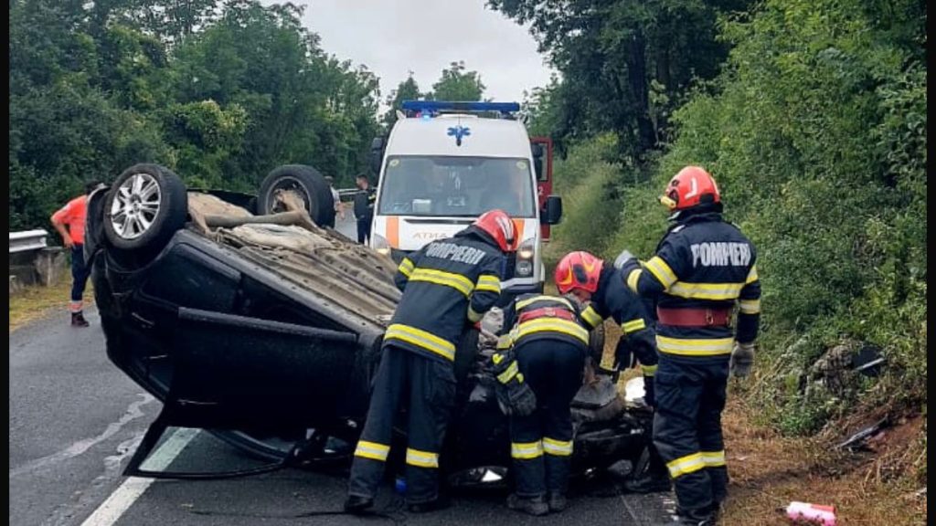 Autoturism răsturnat cu roțile în sus pe marginea drumului național DN 58, la locul unui accident în Caraș-Severin.