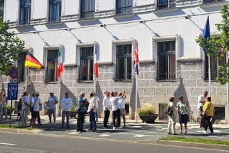 Manifestanți cu pancarte în mâini protestând pașnic în fața Primăriei Timișoara împotriva primarului Dominic Fritz.