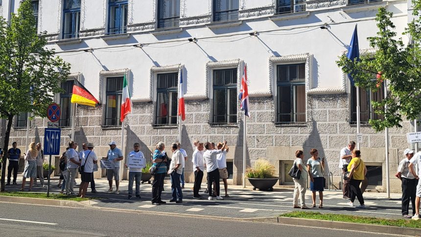 Manifestanți cu pancarte în mâini protestând pașnic în fața Primăriei Timișoara împotriva primarului Dominic Fritz.