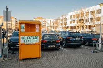 Locuitor din Timișoara introducănd o pungă cu haine vechi într-un container special destinat colectării și reciclării materialelor textile.