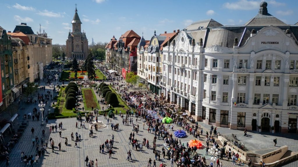 Grup de turiști străini vizitând Piața Unirii din Timișoara, orașul înregistrând o creștere de până la 30% a numărului de vizitatori.