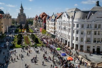 Grup de turiști străini vizitând Piața Unirii din Timișoara, orașul înregistrând o creștere de până la 30% a numărului de vizitatori.