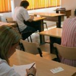 Cadre didactice din județul Timiș susținând proba scrisă a examenului național de titularizare într-o sală de clasă amenajată ca centru de examen.