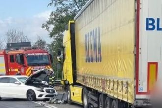 O mașină s-a izbit de un TIR, iar două persoane au fost preluate de ambulanță și duse de urgență la spital.