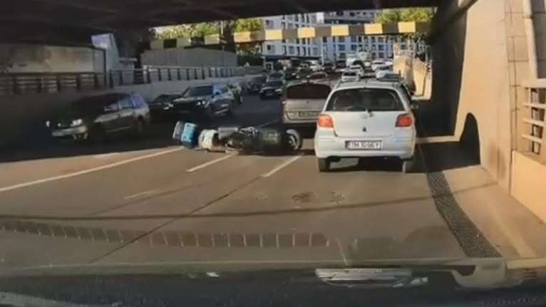 Livrator pe scuter, surprins de o cameră de bord în momentul în care cade pe șosea, sub Pasajul Jiul din Timișoara